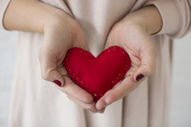 a woman holding a red felt heart 