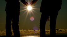 Silhouette of couple holding hands in the moonlight at the beach.