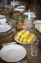 steaming hot corn and turkey on a table set for Thanksgiving dinner 