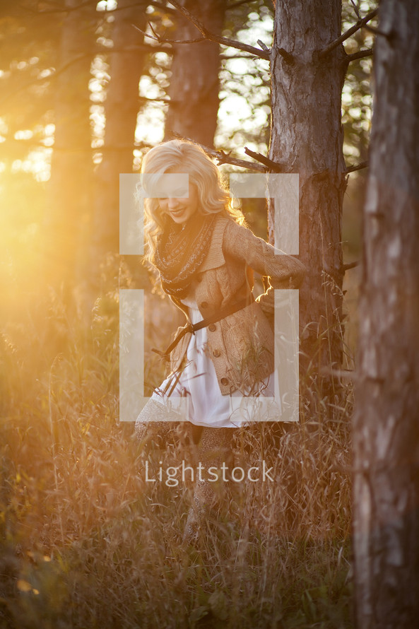 a woman standing in a forest and intense sunlight 