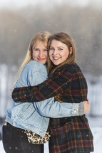 two friends hugging out in snow