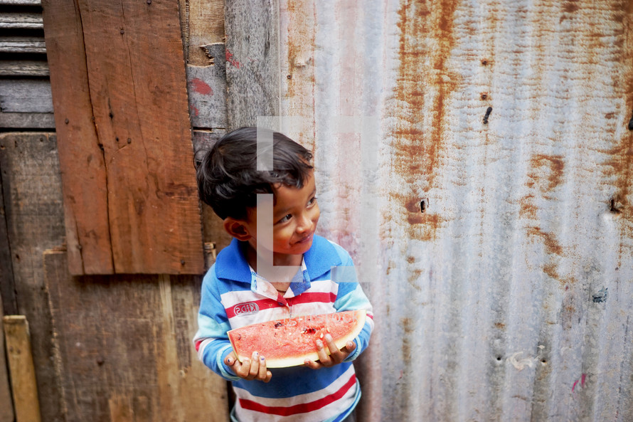 a toddler holding a slice of watermelon 