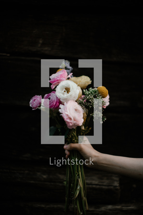 an arm holding out a bouquet of flowers 