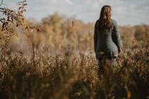 a woman standing in a field in fall 