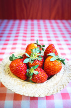 Fresh strawberries decorated on a straw hat. on a red picnic blanket.