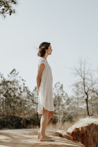 a woman in a dress standing barefoot outdoors 