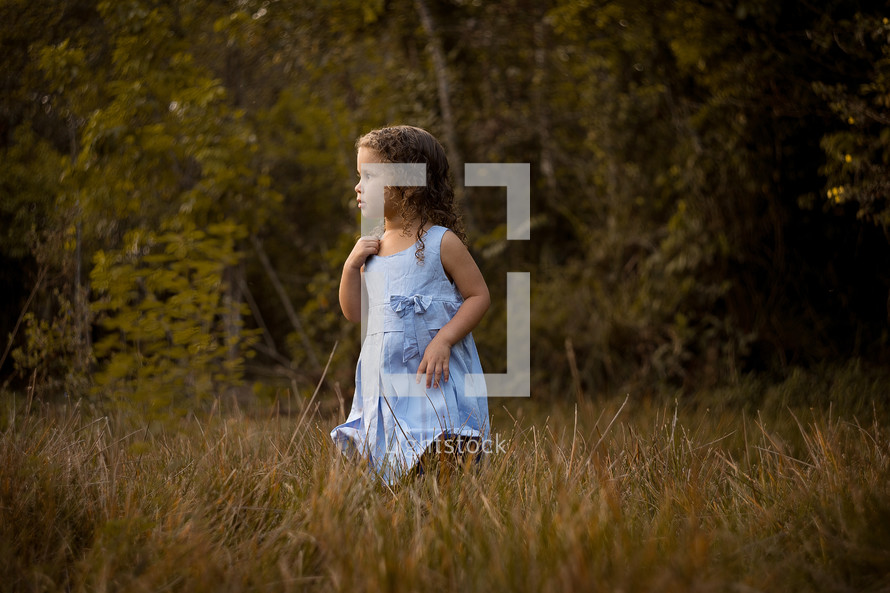 toddler girl standing in tall grass