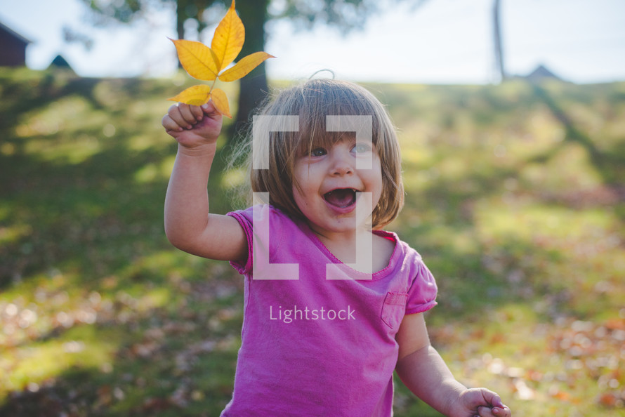girl holding a fall leaf 