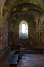 man praying under an arched stone ceiling