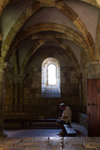 man praying under an arched stone ceiling 