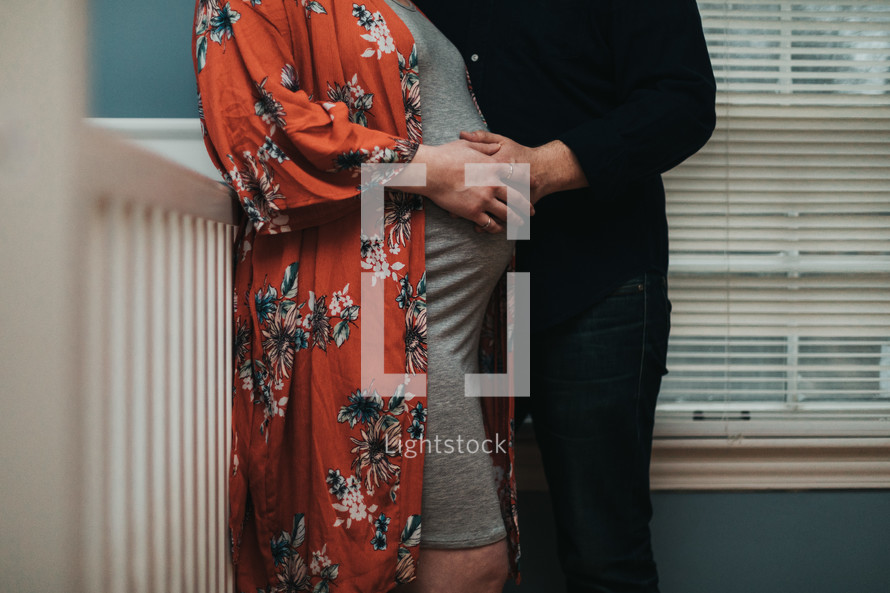 an expecting couple standing in a baby nursery 