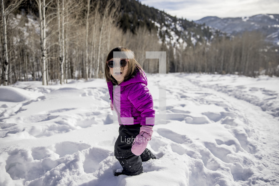 a child in a snowsuit standing in snow 