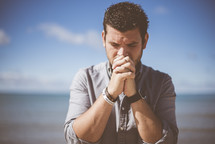 a man praying on a beach 