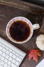 steaming mug of coffee and computer keyboard in fall 