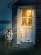 a child leaning against a house at the beach 