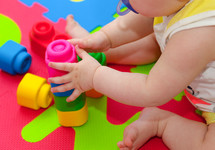 toddler plays with building blocks on the colored rubber mat