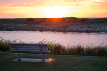 bench along a river at sunset 