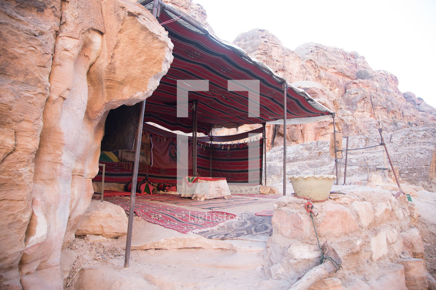 tent against a red rock cliff in Petra