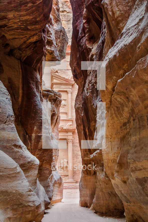 view of through an opening in red rock cliffs Petra, Jordan 