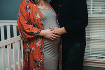 expecting couple standing in a baby nursery 