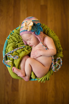 naked newborn in a hat in a basket