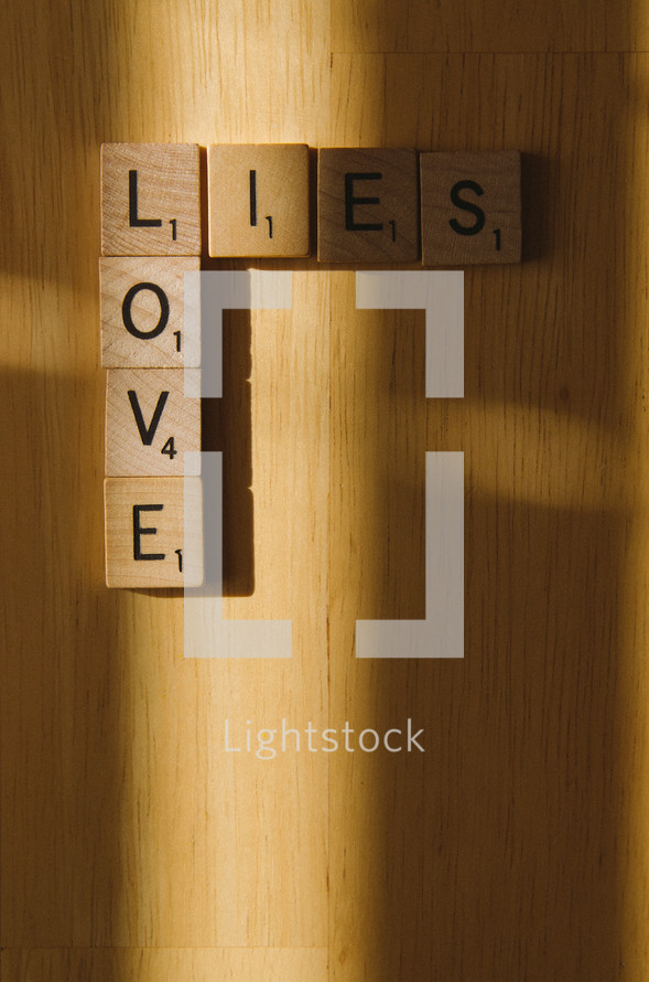 Scrabble tiles arranged to show how love is in the light and lies lead to shadows.