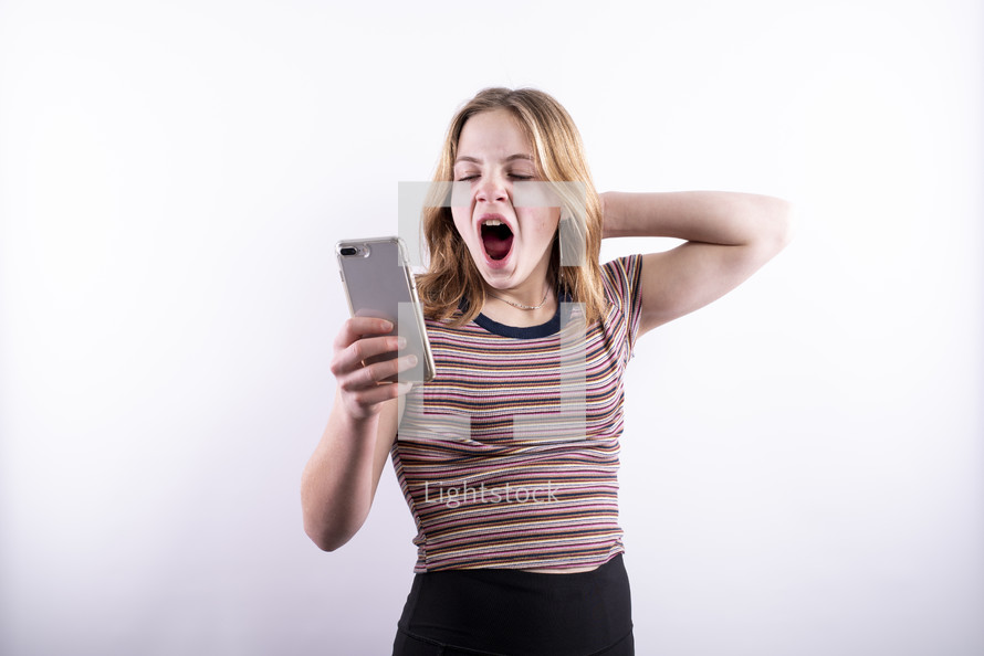 teen girl looking at a cellphone and yawning 