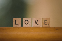 Love spelled out in scrabble tiles on wooden bar.