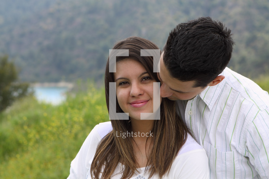 man kissing a woman on the cheek outdoors