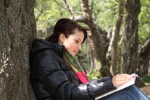 woman reading a Bible against a tree outdoors