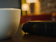 Holy Bible and coffee mug on a table 