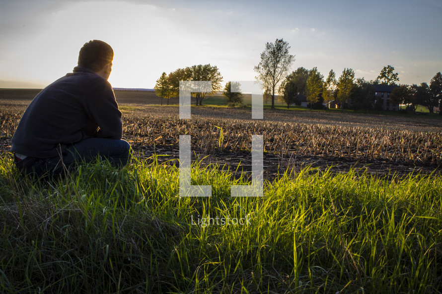 man sitting in a freshly plowed field 