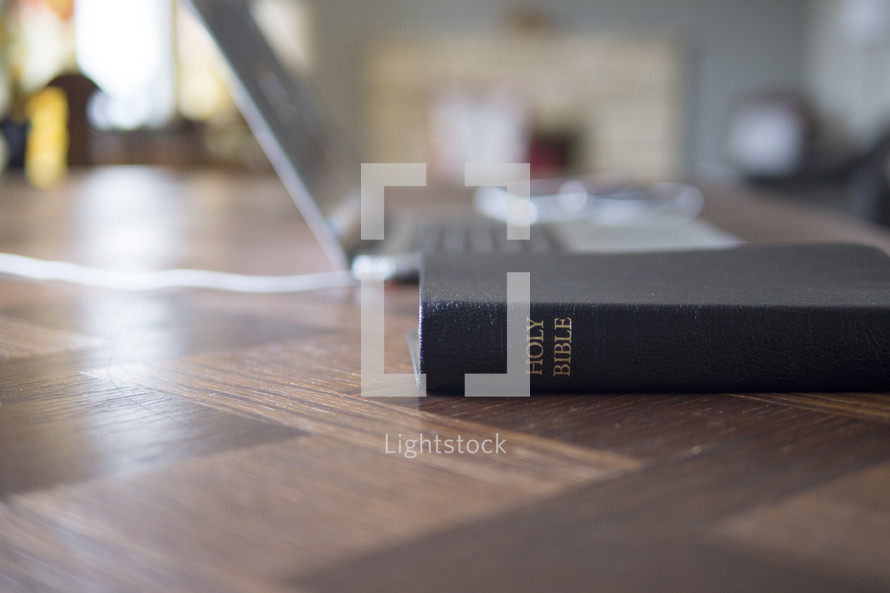 Holy Bible and laptop on a desk 