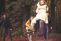 teens on a tire swing in a forest 