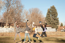 college students jumping up and down holding Bibles outdoors during a Bible study