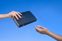 hand giving a Bible