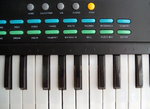 Upclose view of an electronic keyboard with piano keys, programmable buttons for different styles of music and synthesized sounds to emulate for a concert or recording session for praise, worship and contemporary Christian music bands on tour or recording live in a recording studio. 