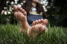dirty bare feet on a woman sitting in grass 
