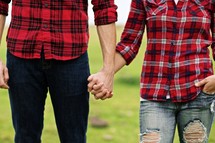 Couple in plais shirts holding hands.