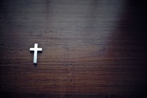 Cross pendant  on a wood table.