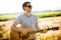 man playing an acoustic guitar outdoors 