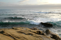 Ocean waves crashing onto rocks on shore.