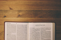 Bible on a wooden table open to the book of Leviticus.