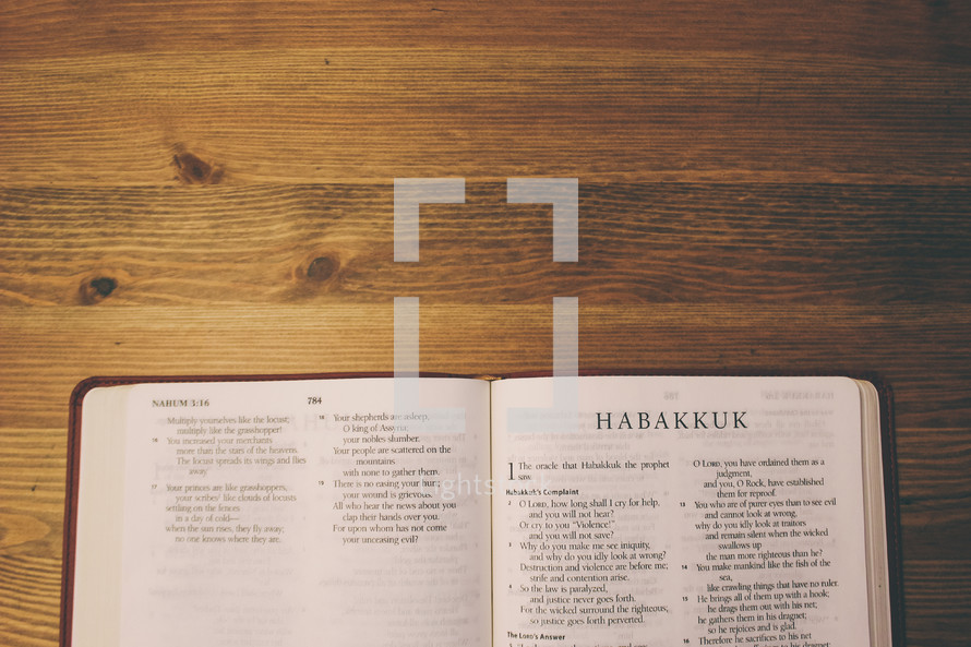 Bible on a wooden table open to the book of Habakkuk.
