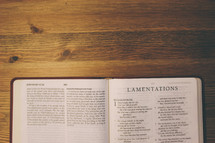 Bible on a wooden table open to the book of Lamentations.