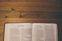 Bible on a wooden table open to the book of Jonah.