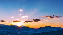 Colorful sunrise over alpine mountains in blue spring sky in morning countryside landscape time-lapse
