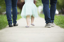 mother, father, and toddler daughter, walking holding hands 