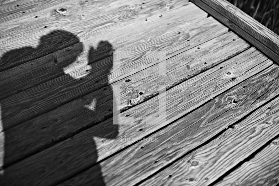 The shadow of a person praying on a dock