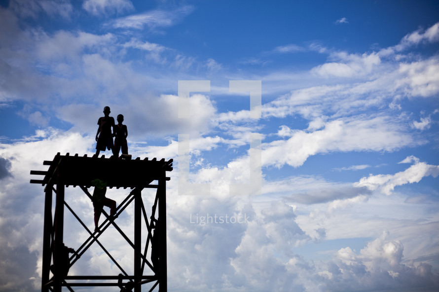 children climbing and standing on a roof under a blue sky